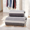 A stack of gray and white striped microfiber bath towels on a wooden floor.