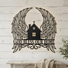 Black metal wall art featuring a silhouette of wings surrounding a house with a cross and the text God Bless Our Home