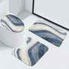 A set of three striped blue and beige non-slip bathroom mats placed on a white toilet tank.