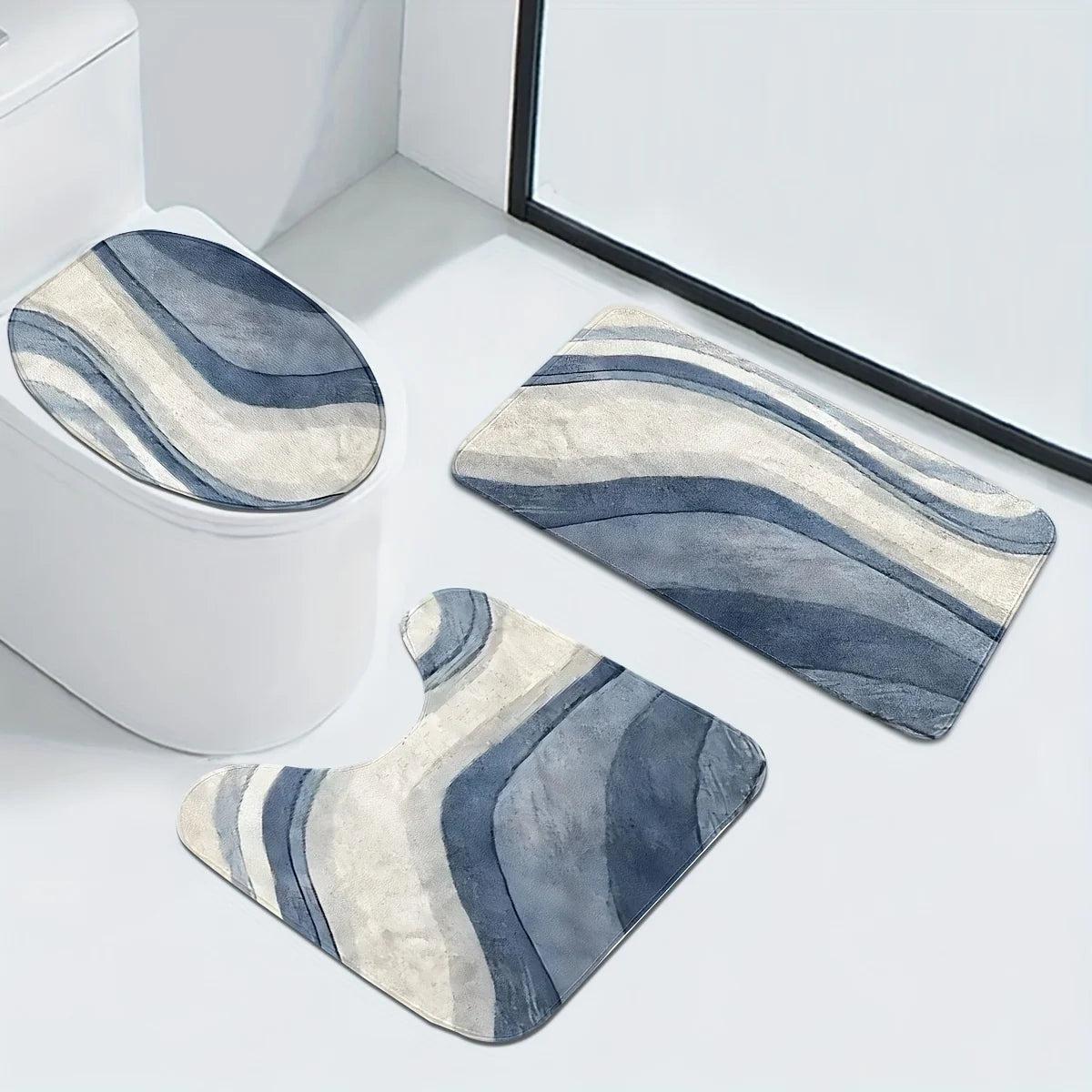 A set of three striped blue and beige non-slip bathroom mats placed on a white toilet tank.