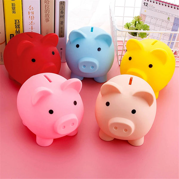 Four colorful vinyl piggy banks in red, blue, yellow, and pink sitting on a pink surface.