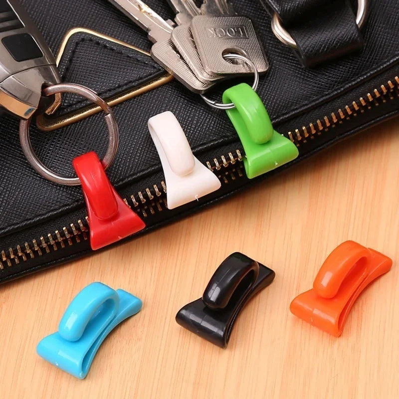A pack of colorful key holder clips in red, white, green, black, and orange resting on a black zippered pouch.