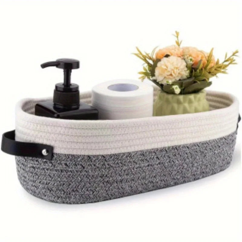 A woven cotton storage basket holding a black pump dispenser and a roll of white paper towels next to a bouquet of orange and
