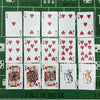 A set of poker playing cards arranged in a grid on a green surface.