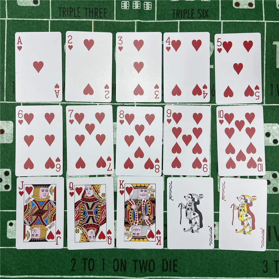 A set of poker playing cards arranged in a grid on a green surface.