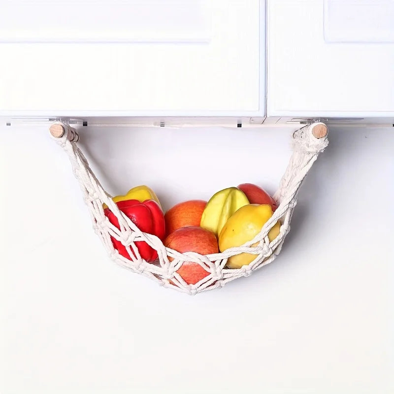 A woven sisal fruit hammock storage basket filled with various colorful fruits on a white surface.