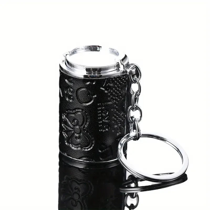 A black metal coin tube keychain with a silver top and a silver ring attached.