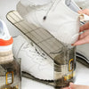A clear plastic shoe organizer rack holds a pair of white sneakers.