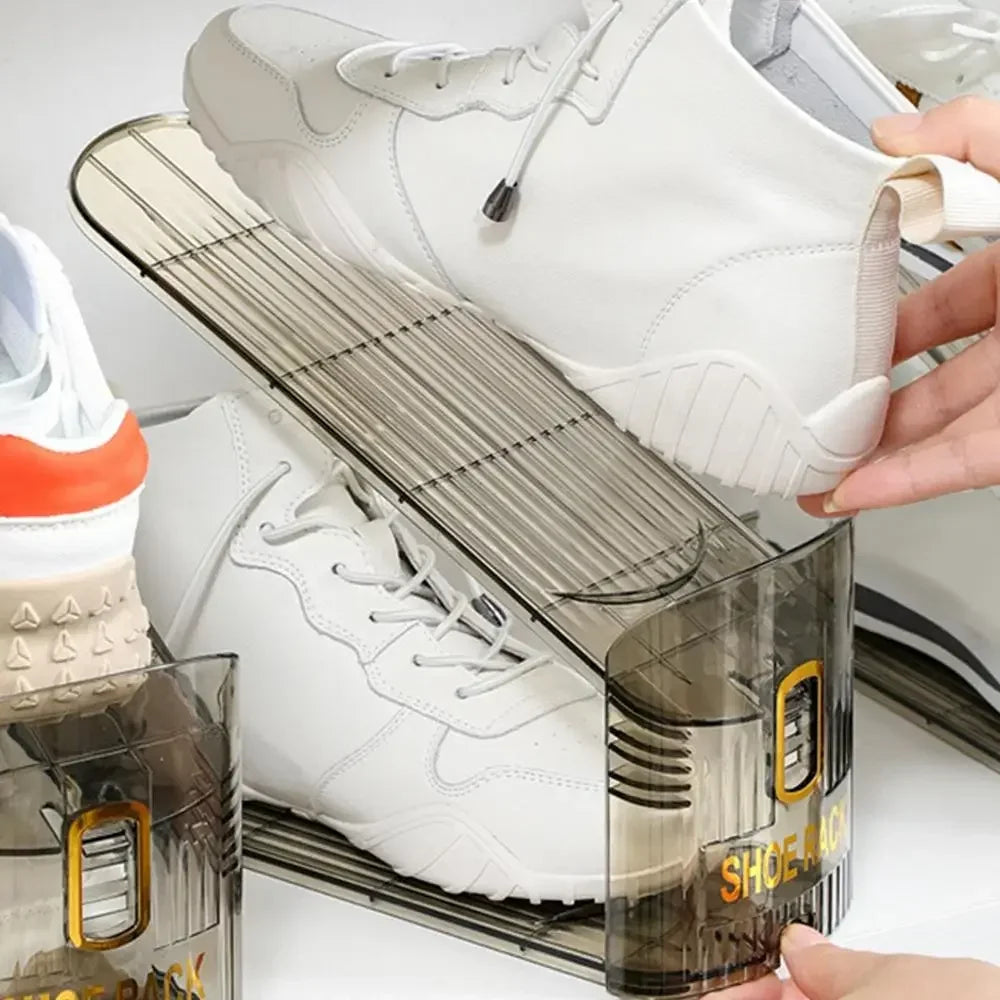 A clear plastic shoe organizer rack holds a pair of white sneakers.