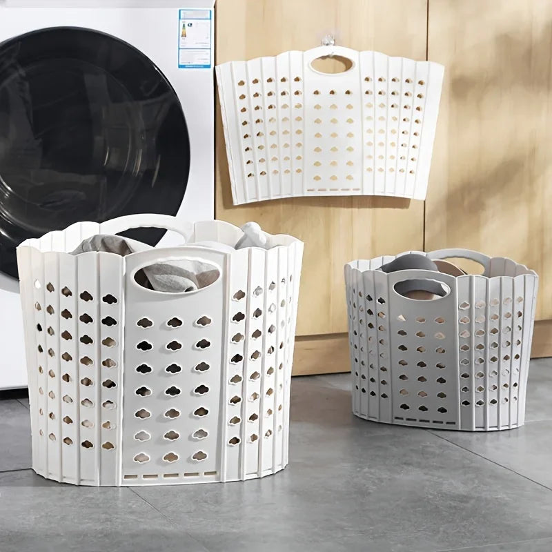 White folding hand-held clothes storage basket with perforated design displayed on a gray floor.