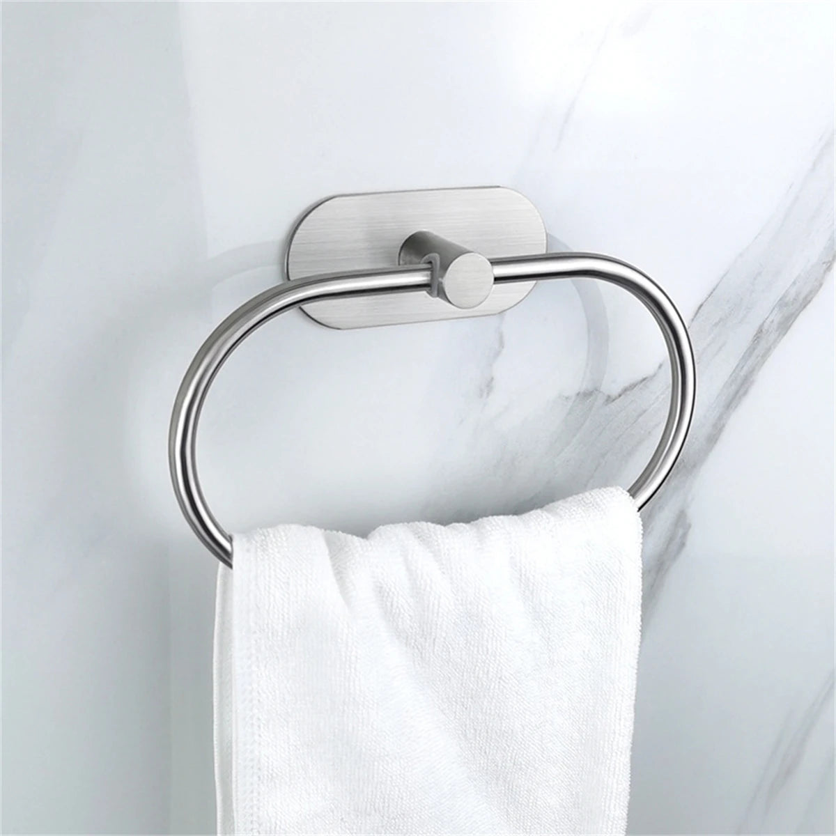 Estante adhesivo de toallas de acero inoxidable montado en la pared, sosteniendo una toalla blanca.