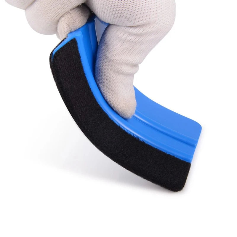 A hand is holding a blue suede felt squeegee with a black rubber edge for vinyl wrap installation.
