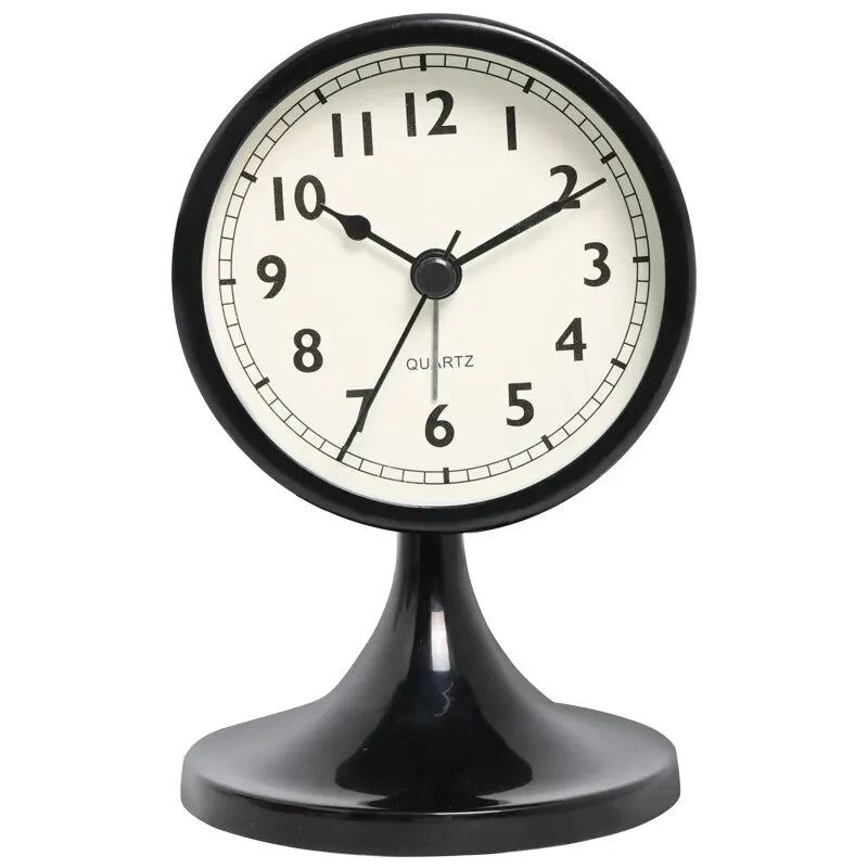 A black round analog alarm clock with a white face and black hands sitting on a pedestal.