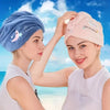Two women smiling while applying a soft absorbent hair towel to their heads on a beach background.