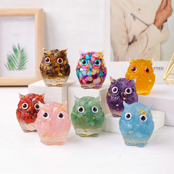 A collection of seven colorful crystal crushed stone owl drip ornaments displayed on a white surface.