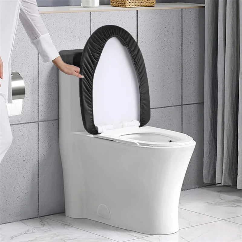 A white toilet with a black velvet seat and tank protectors installed in a bathroom setting.