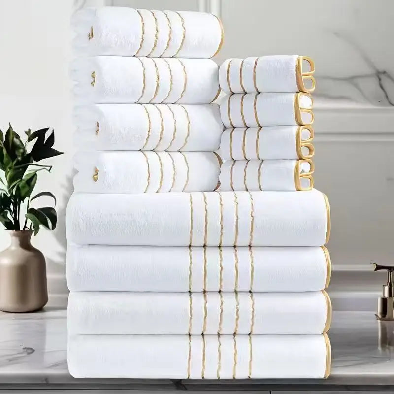Ein Stapel weißer Badetücher mit goldenen Streifen, verschiedene Größen und Texturen.