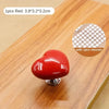 Un bouton de chasse d'eau en forme de cœur rouge sur une surface en bois.