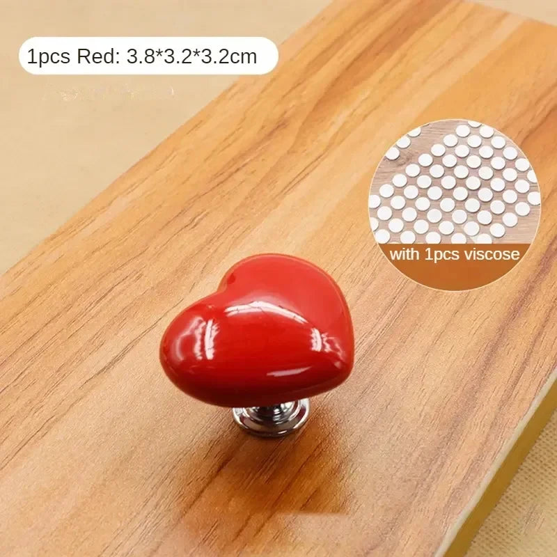 Un bouton de chasse d'eau en forme de cœur rouge sur une surface en bois.