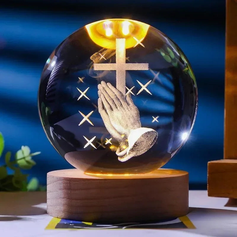 A glass crystal ball with a golden light showing a cross and a praying hand silhouette.