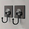 Two modern, rectangular metal wall hooks with black curved hangers mounted on a light gray wall.