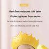 A yellow crown-shaped shampoo cap is shown on a baby's head, designed to prevent water from flowing backward.