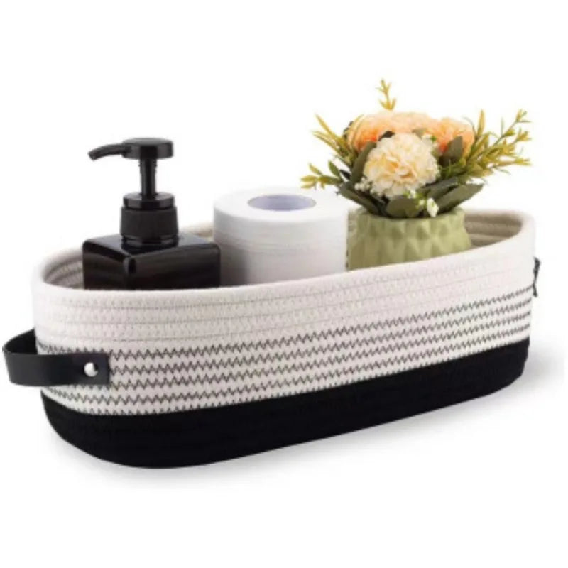 A woven cotton storage basket with a black lid and a white roll of paper inside, decorated with dried flowers.