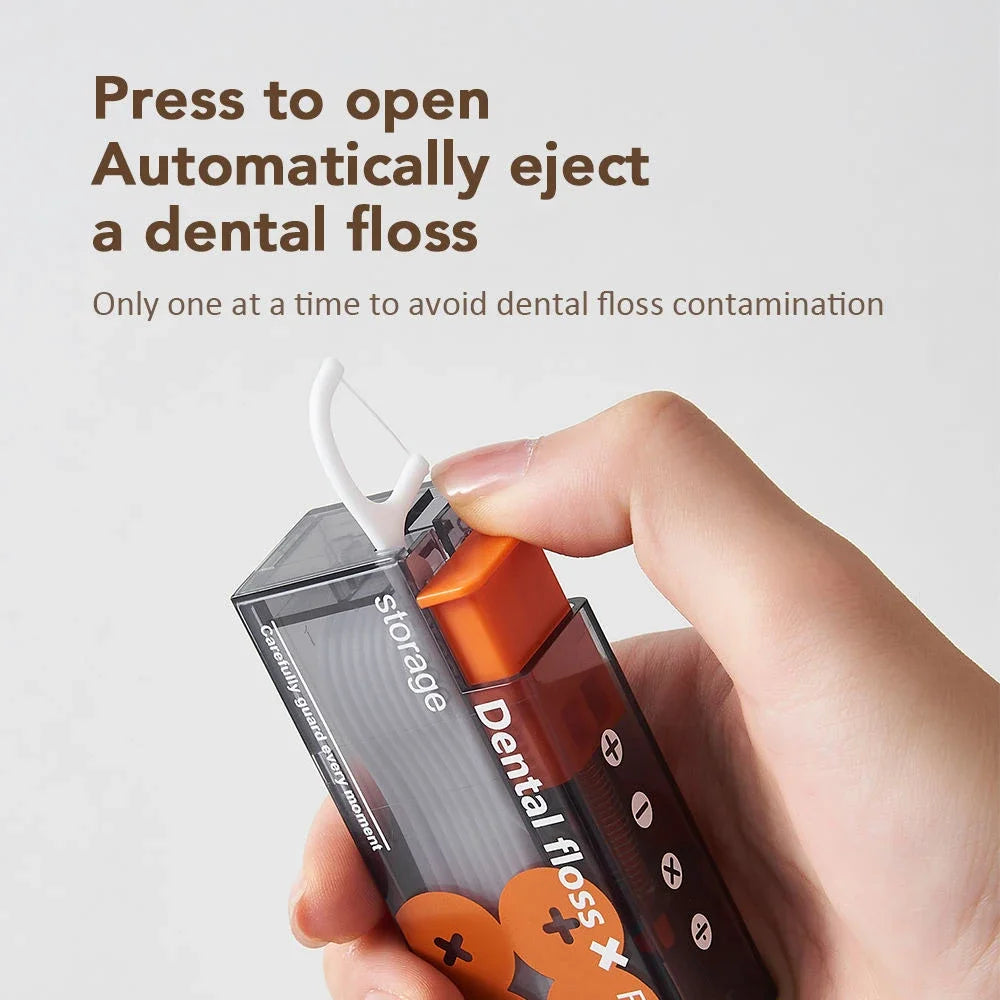 A hand is pressing a portable automatic floss storage dispenser to eject a dental floss strand.