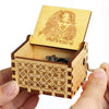 An antique wooden hand crank music box with a light wood box featuring an engraved face design.