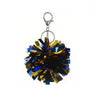 Glänzendes blau-goldenes Pom-Pom-Anhänger mit Metallhaken.