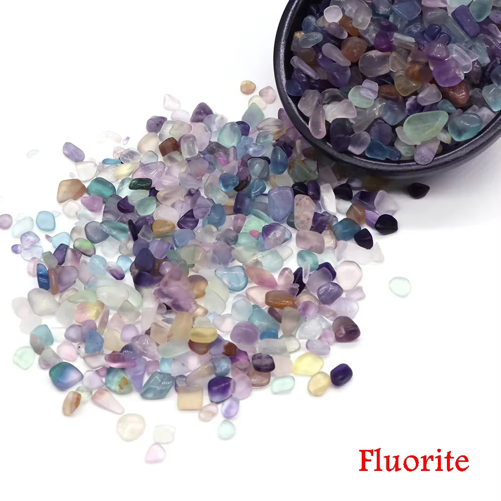 Pila de cristales de fluorita de varios colores, incluyendo tonos morados, azules y verdes, exhibidos junto a un cuenco oscur