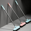 Three long-handle floor scrub brushes in pink and light blue colors are displayed against a gray wall.