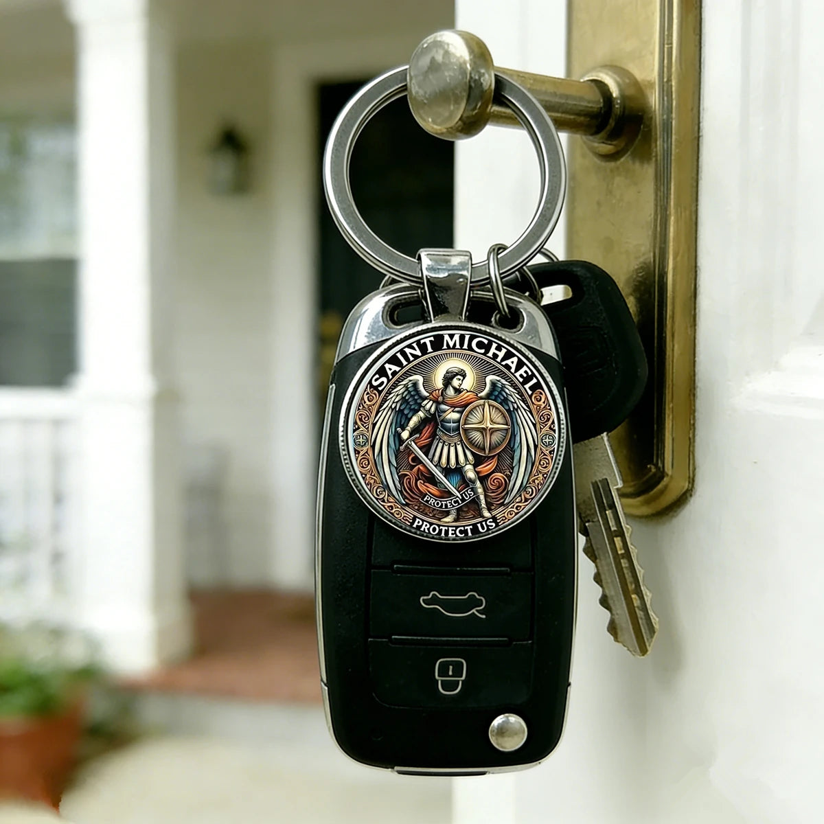 A black keychain featuring a silver medallion of Saint Michael the Archangel, attached to a brass door hook.
