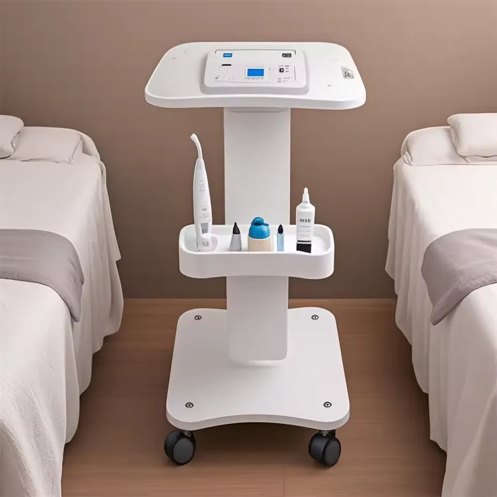 A white portable beauty trolley cart with a top station for tools and a rolling base is shown in a bedroom setting.
