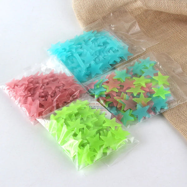 A collection of glow-in-the-dark star wall decals in various shades of blue, pink, and green packaged in clear plastic.