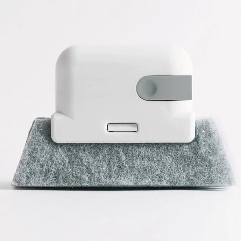 A white window and gap cleaning brush resting on a gray, fibrous cleaning mat.