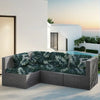 Cubierta de sofá exterior con estampado de hoja tropical verde oscuro en un patio junto a una casa moderna blanca y piscina.