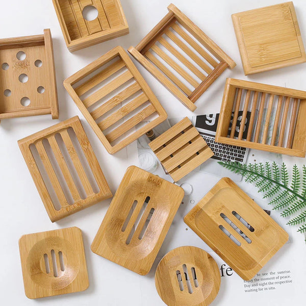 A collection of wooden bamboo soap dish holders in various shapes and sizes arranged on a white surface.