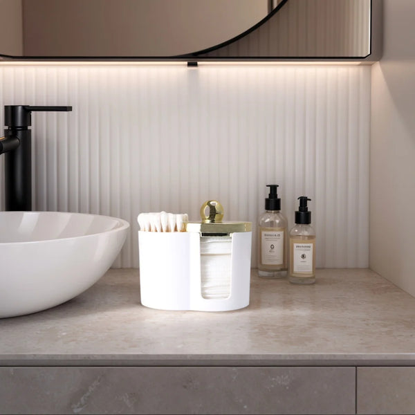 A white plastic bathroom organizer holds cotton swabs and makeup accessories on a marble countertop.