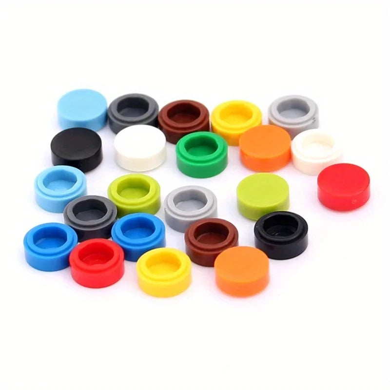 A collection of round building blocks in various colors including blue, black, white, green, orange, and gray.