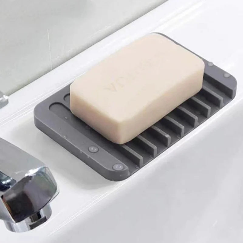 A beige silicone soap dish with an anti-slip base is placed on a white sink surface.