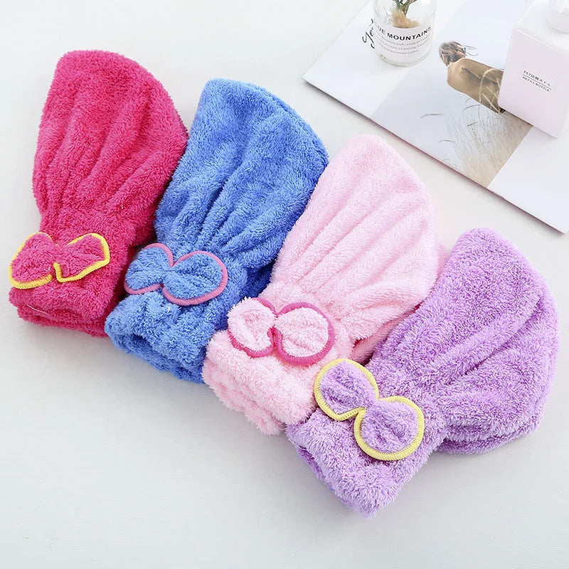 A set of three fuzzy microfiber hair drying towel caps in pink, blue, and purple are displayed on a white surface.