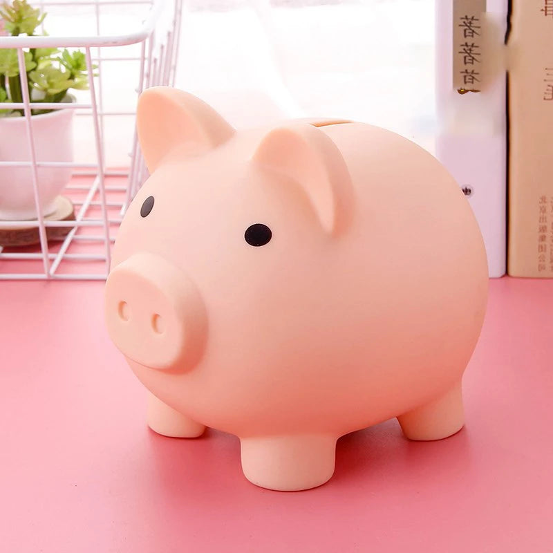 A pink vinyl piggy bank with black eyes sitting on a pink surface.