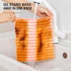 Hands are rinsing orange microfiber kitchen dish cloths in a white bathtub, demonstrating easy oil stain removal.
