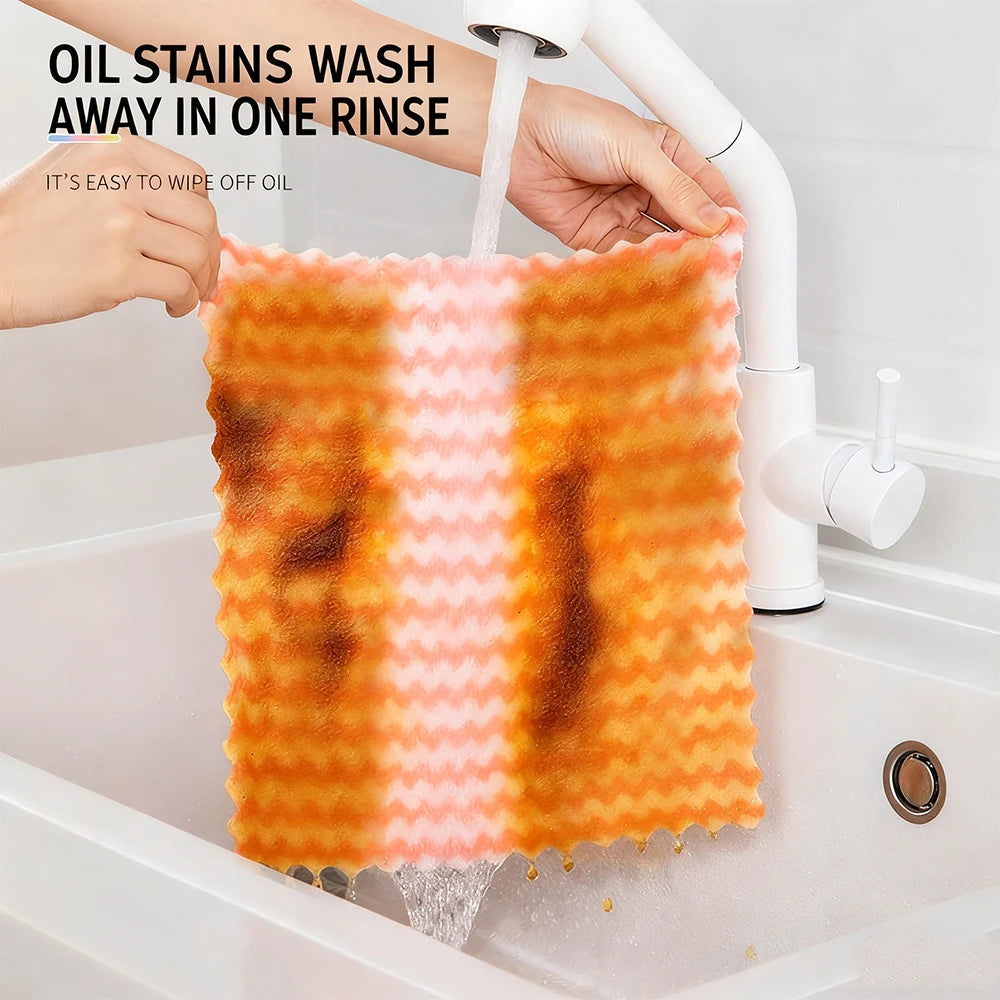 Hands are rinsing orange microfiber kitchen dish cloths in a white bathtub, demonstrating easy oil stain removal.