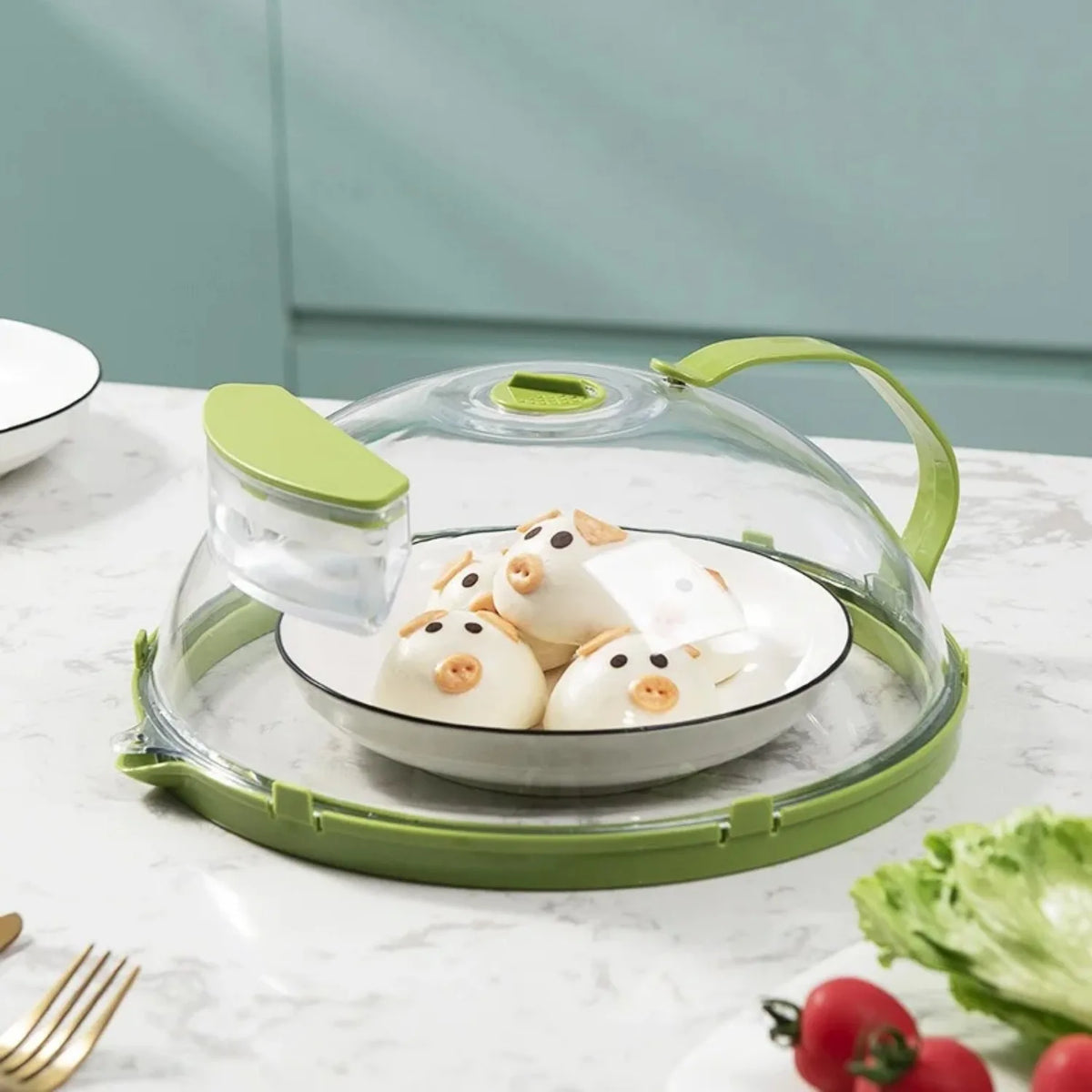 A clear microwave splatter cover with a water steamer is shown resting on a green tray.