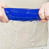 A hand is dripping water from a bright blue thickened microfiber cleaning cloth onto a surface.