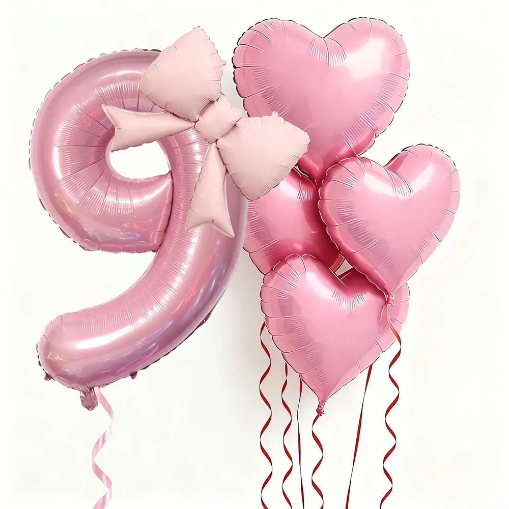 Un set de seis globos de aluminio con forma de corazón rosa que forman el número 9, atados con una cinta rosa.