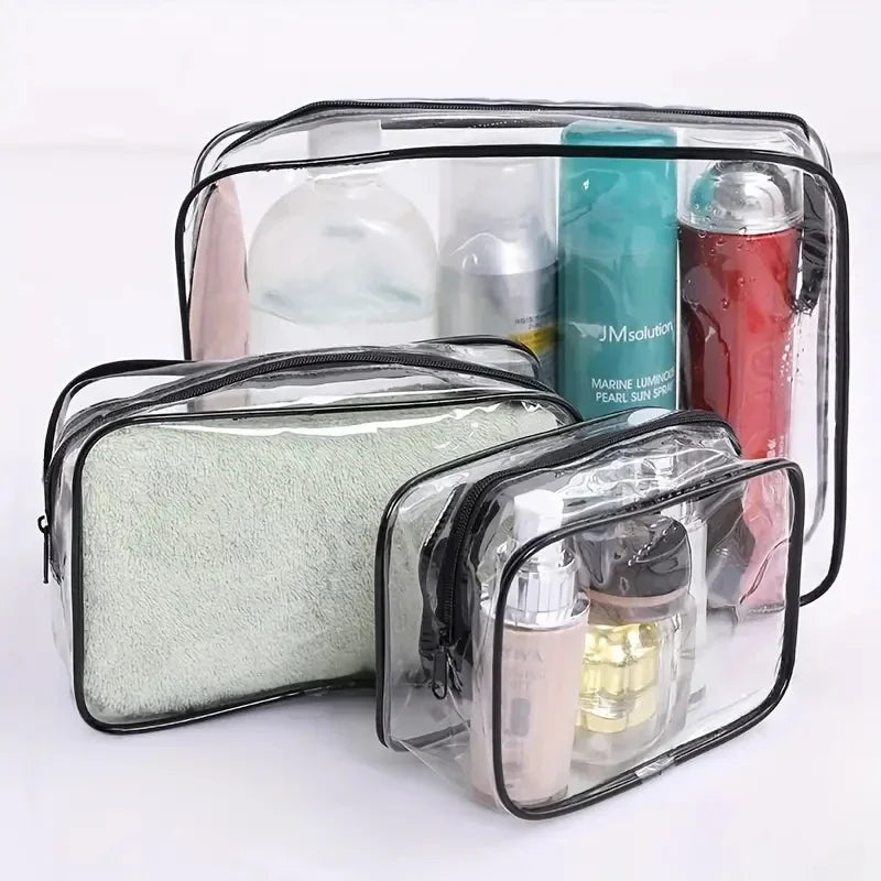 A set of three clear plastic travel makeup organizer bags containing various cosmetic products.