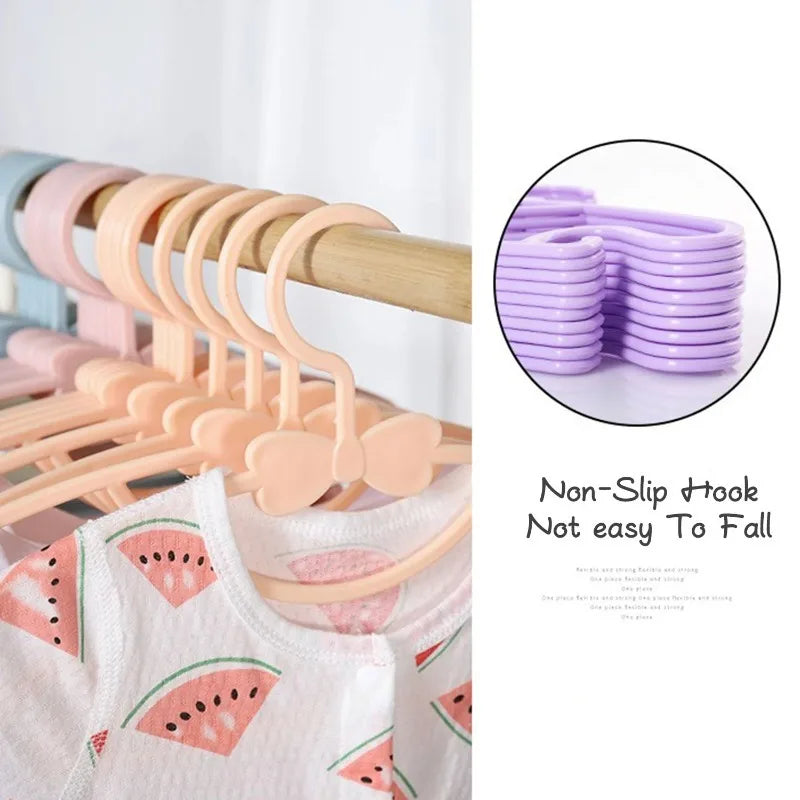 A set of pink plastic hangers with bow designs and windproof locks for children's clothing.